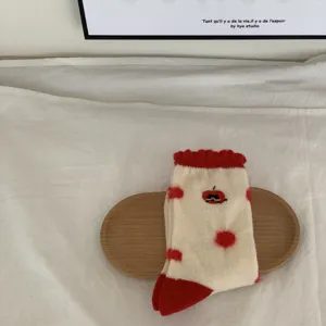 Detalle de calcetines de invierno suaves, diseño crema con topos rojos y tela acogedora.