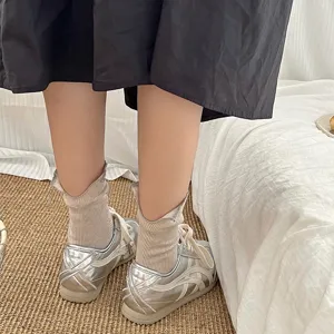 Detail shot of ribbed mid-calf socks with back slit design, paired with stylish silver sneakers.