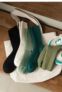 Detailaufnahme gemütlicher gerippter Socken in bunten Herbstfarben auf einer Stofftasche.