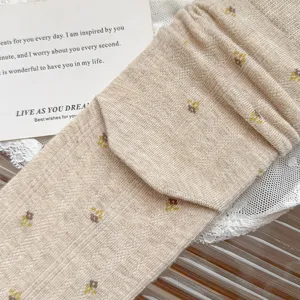 Close-up detail of beige cotton floral stacked socks, soft knit fabric with tiny flower pattern.