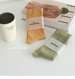 Detail shot of Morandi color slouch socks, featuring soft fabric and neat paper band packaging.