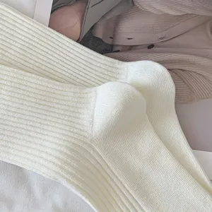 Cream white ribbed knit slouch socks, cozy winter mid tube cotton socks close up view texture.