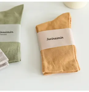 Detailed close-up view of folded solid color Morandi style slouch socks with paper wrap bands.