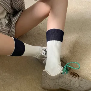 Close-up detail of soft cotton slouch socks with color block contrast cuffs and ribbed knit.