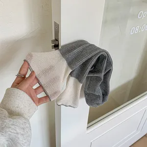 Grey and cream colorblock knitted crew socks close-up, ribbed texture detail, cozy winter socks.