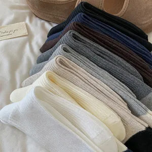 Detailed shot of stacked ribbed cotton slouch socks in multiple colors, featuring soft texture.