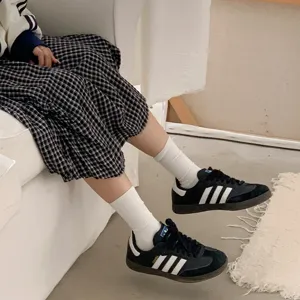 Classic white mid-tube socks paired with casual sneakers and plaid skirt, daily outfit detail.