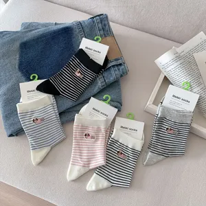 Detailed view of striped cotton mid-tube socks with cute dog embroidery and paper tag.