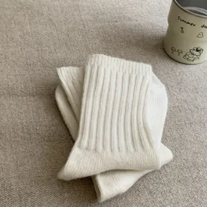 Close-up detail of cozy white wool mid-tube knit socks with classic cable texture.