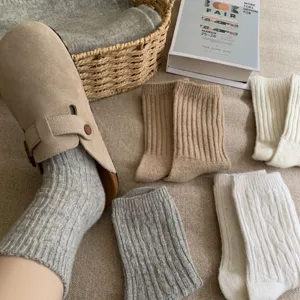 Close-up of cozy knit cable socks paired with slip-on clogs in a warm lifestyle setting.