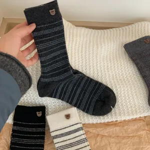 Detailopname van warme gestreepte dames sokken met schattige kleine berenknopjes.