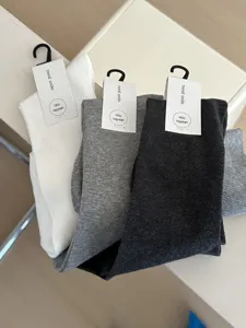 Closeup detail of soft solid color over-the-knee ribbed socks featuring hanging product tags.