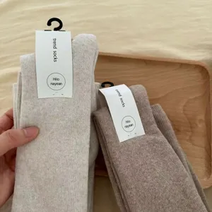 Thick over-the-knee winter knit socks detail view, showing soft fabric texture and paper tags.