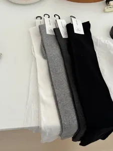 Over-the-knee socks detail shot showing soft texture and four classic solid colors neatly laid.
