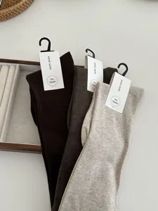 Detail view of solid color ribbed over-the-knee long socks with hanging tags for women