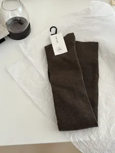 Close-up of dark brown over-the-knee socks displayed with brand tag on clean white background.
