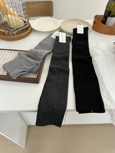 Detail shot of over-the-knee socks in gray and black, neatly arranged on a clean white desk.