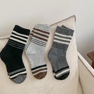 Vue détaillée de chaussettes en laine épaisses et rayées sur coussin, parfaites pour l'hiver.