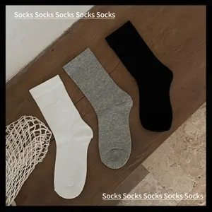Détail de chaussettes mi-hautes unies classiques, disponibles en noir, blanc et gris.