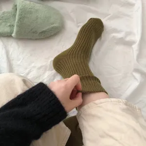 Primo piano di calze medie a coste in lana verde oliva da donna, stile accogliente e casual.
