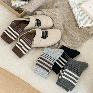 Vue détaillée de chaussettes montantes en laine rayées confortables sur fond tricoté.