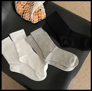 Vue détaillée de chaussettes unies classiques en noir, blanc et gris avec larges bords côtelés.