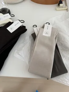 Detail view of cozy wool blend long socks with product tags on white minimalist table.