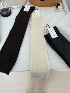 Detailed view of solid color lambswool cashmere long calf socks in dark brown, beige, and grey.