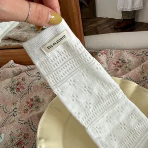 White hollow-out knit mid tube socks detail showcasing breathable mesh texture and cloth label.