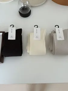 Close-up detail of three pairs of soft wool blend mid-calf socks in brown, cream and grey.