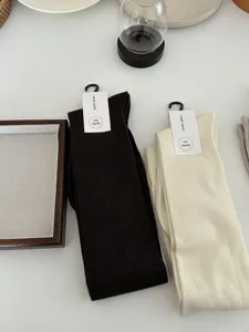 Detail shot of soft wool blend long socks in dark brown and cream colors with paper tags.