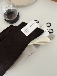 Close-up detail of soft wool blend winter calf socks with tags, neatly stacked on white table.