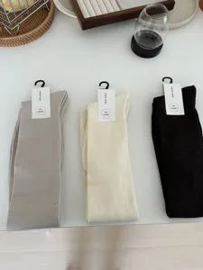 Detailed view of cozy knit long socks in grey, beige and dark brown, flat lay setup.