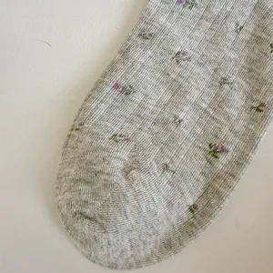 Primer plano de calcetines grises para mujer con estampado floral, transpirables.