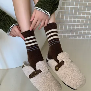 Gros plan détaillé de chaussettes en laine rayées chaudes avec des sabots en peluche.