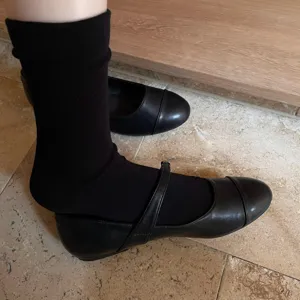 Gros plan détaillé de chaussettes noires portées avec des chaussures sur carrelage.