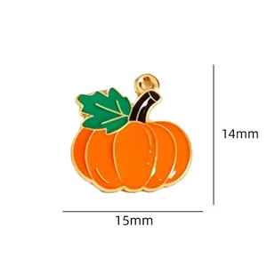 Detail shot of a gold-trimmed enamel pumpkin pendant with green leaf, ideal for DIY autumn charm.