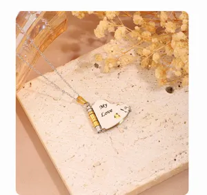 Close-up detail of stainless steel heart letter locket necklace with delicate engraved text.