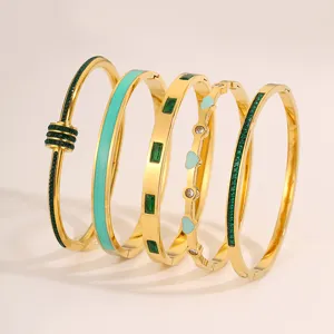 Set mit fünf eleganten Edelstahl vergoldeten Armreifen mit grünen Steinen und Emaille-Designs.