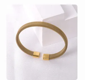 Close-up detail of the gold-colored woven mesh cuff bracelet, showing texture and open end.