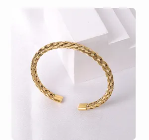 Close-up of golden braided cuff bracelet showcasing intricate metal texture and polished finish.