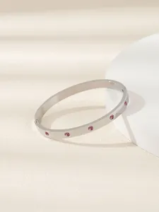 Vista dettagliata di un bracciale rigido in acciaio inox con pietre rosa, raffinato gioiello da donna.
