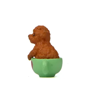 Schattige bruine teddy hond in groene kop figuur, miniatuur hars cartoon tuin pop detail.
