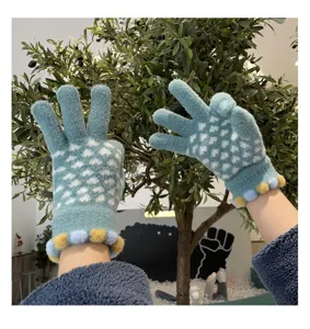 Detail view of winter warm knitted touch screen gloves with cute pom-poms for women.