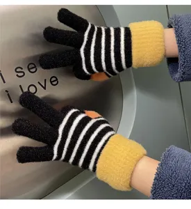 Close-up detail of winter warm knit gloves with black white stripes and soft yellow cuffs.