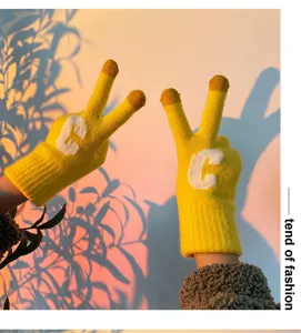 Close up of yellow knitted winter gloves with letter C, warm cozy sunset aesthetic style.