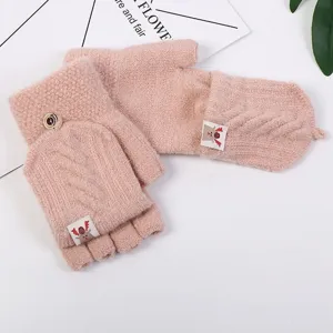 Close-up detail of women winter knit fingerless convertible gloves in pink wool with cute deer tag.
