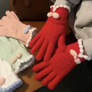 Primo piano dettagliato di guanti in maglia con fiocco, bordo soffice e perla d'inverno.