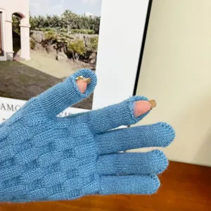 Close-up of winter knitted blue fingerless gloves, showing fine cable knit texture and detail.