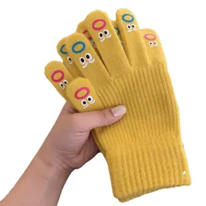 Close-up detail of cute yellow knitted winter gloves with funny embroidered face patterns.